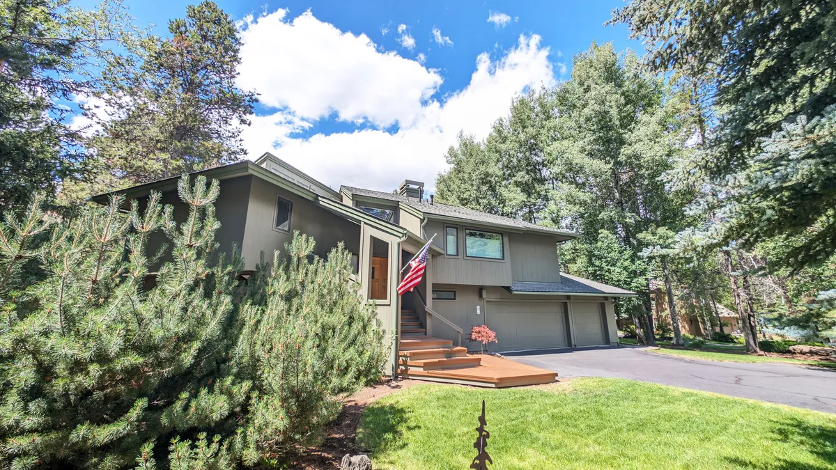 Another exterior perspective of the home, highlighting the front steps, American flag, and lush garden. The angle emphasizes the approachable entryway and the tranquility of the setting, reinforcing the sense of retreat and comfort.