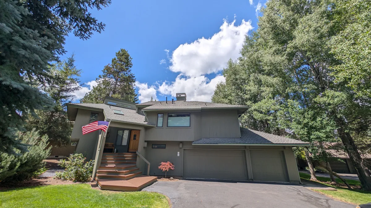 This exterior shot features the welcoming front entrance of the home, adorned with an American flag and surrounded by a thoughtfully landscaped garden. The inviting porch suggests a relaxing space to enjoy the outdoors, whether for morning coffee or evening sunsets.