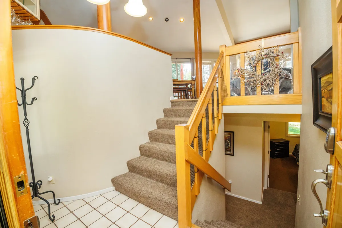 Taken just inside the entry, this interior shot captures a warm, inviting staircase with a view of the dining area beyond. The openness and warmth of the space suggest easy transitions between work and leisure, and the background hints at communal meals and gatherings.
