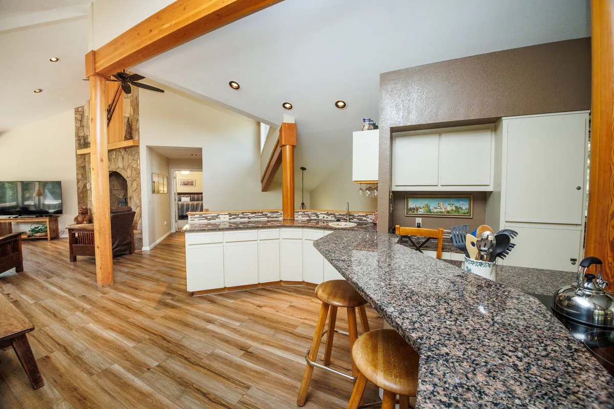 A stylish, modern kitchen featuring granite countertops, stainless steel appliances, wooden beams, and an open layout—ideal for cooking, entertaining, and family gatherings.