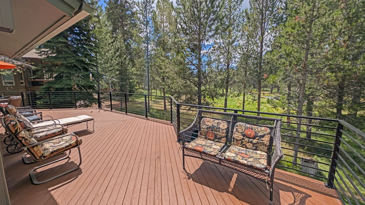 A tranquil wooden deck with comfortable seating nestled among tall trees, the setting offers a peaceful space for relaxing, sipping morning coffee, or stargazing at night.